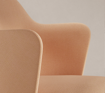 Close-up detail of the Aleta chair by Jaime Hayon for Viccarbe, showing the curved backrest and armrest in peach-coloured upholstery.