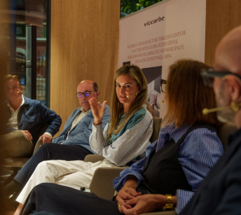 Speaker gesturing mid-conversation at the Flex Living round table, with other participants seated beside her